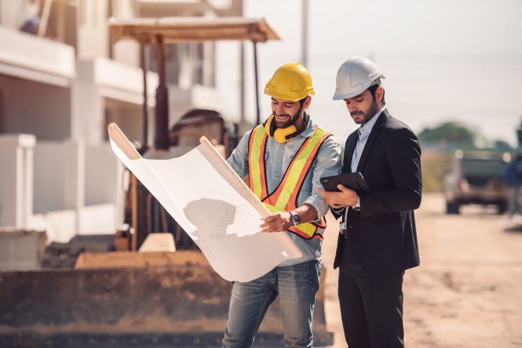 Two men at a construction site reviewing a blueprint
